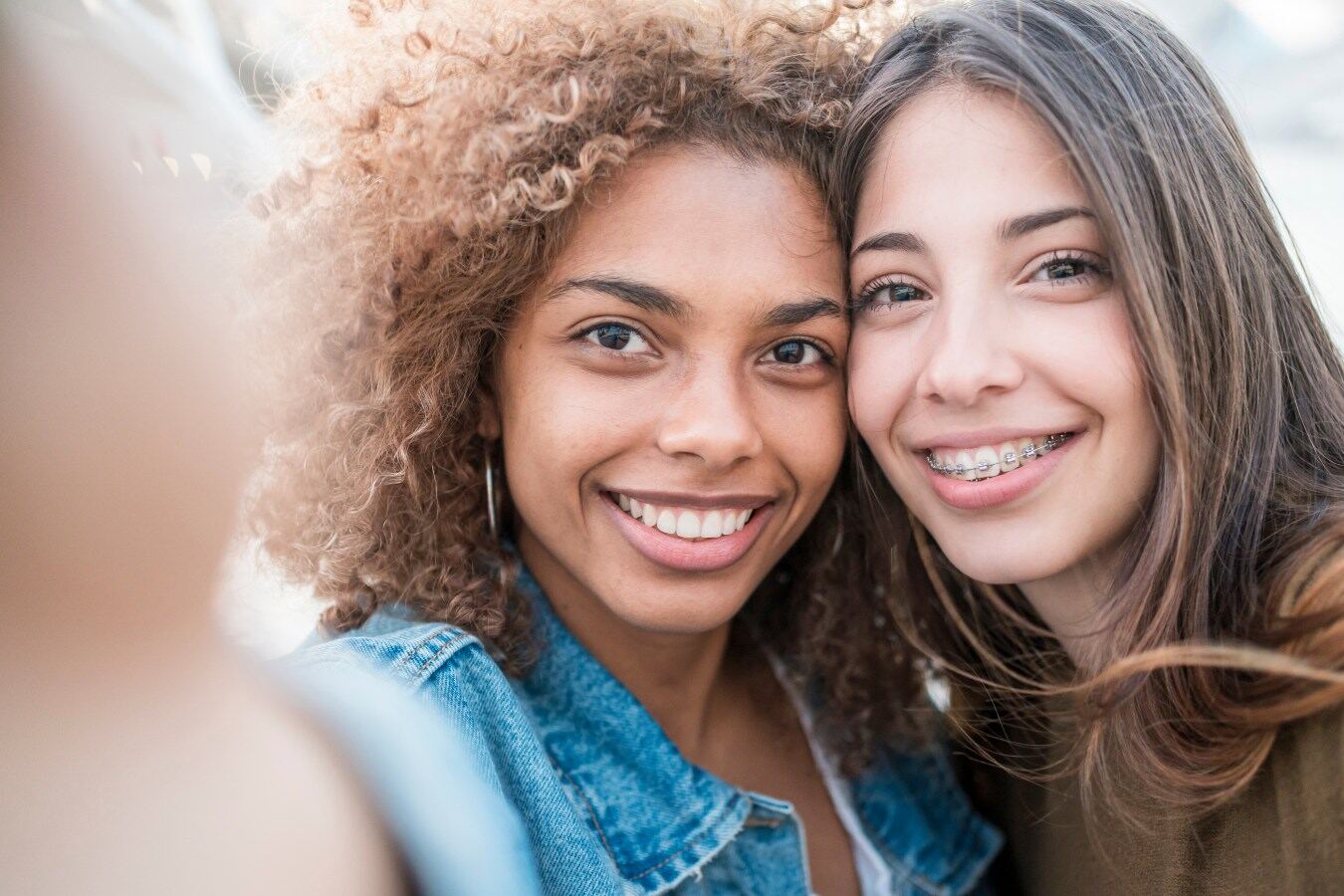Two smiling teens, one wearing braces