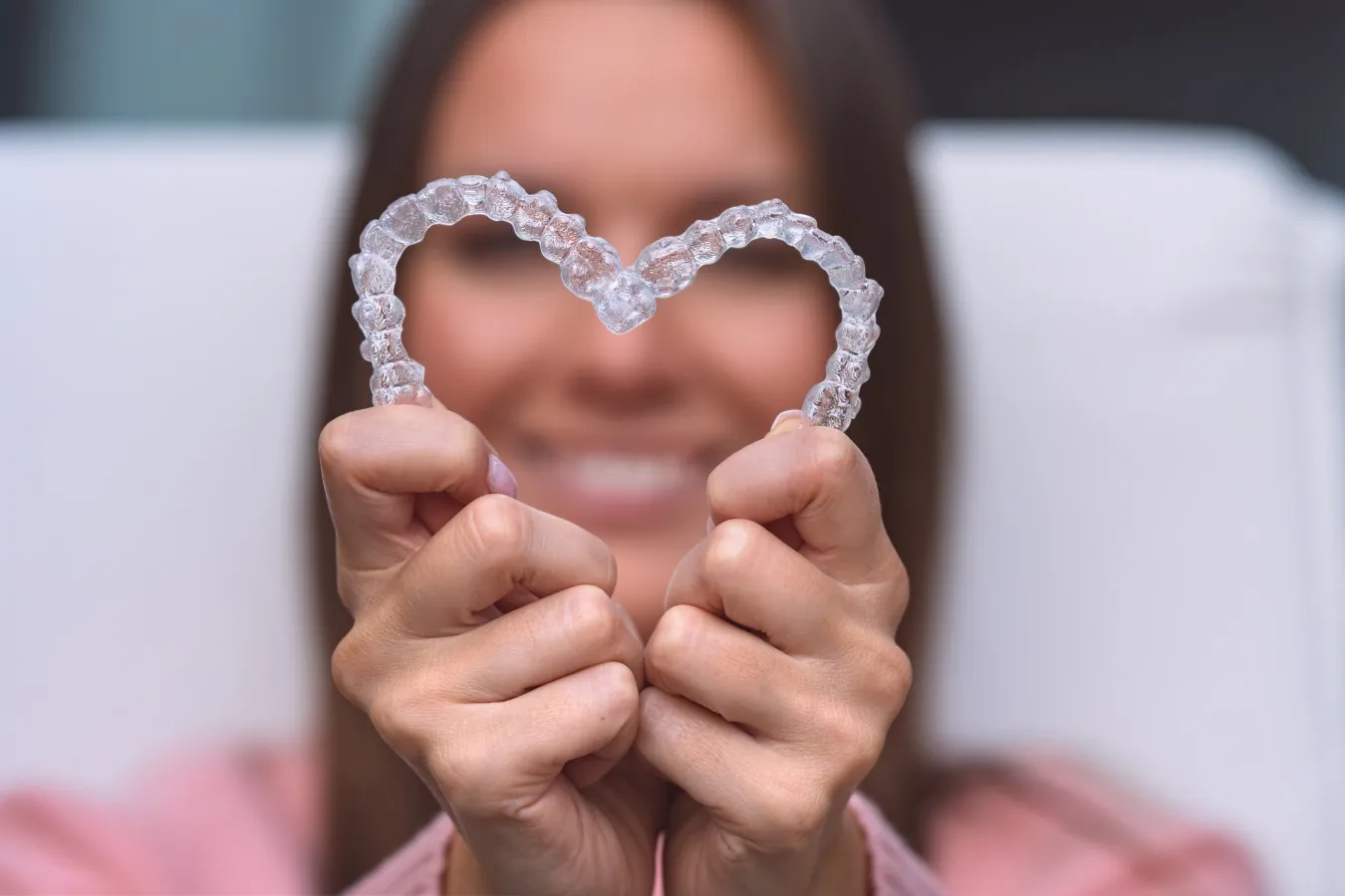 Hands forming a heart with a clear aligner