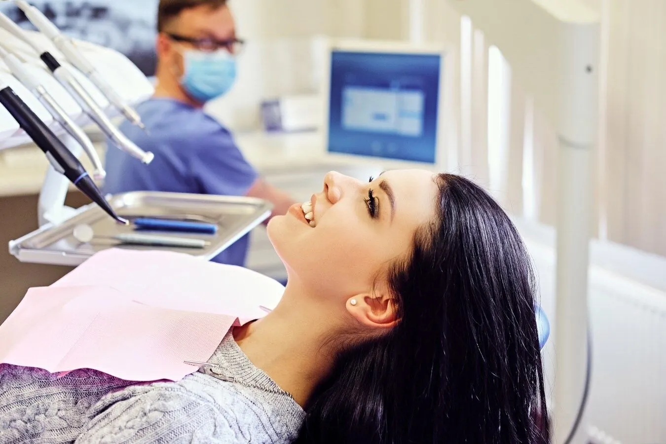 Patient smiling in a dental chair while a clinician prepares