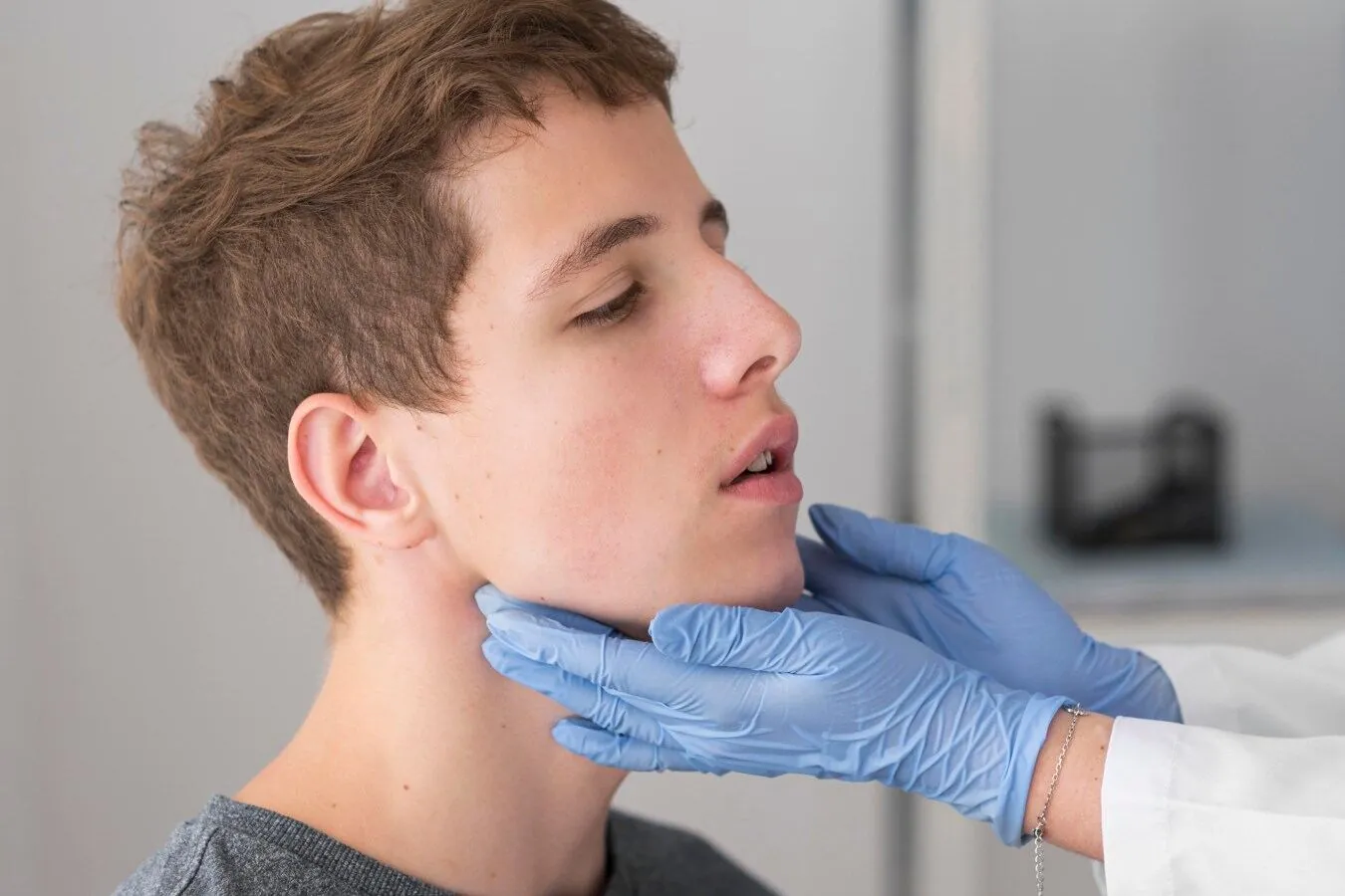 Clinician examining a young man's jaw for TMD symptoms